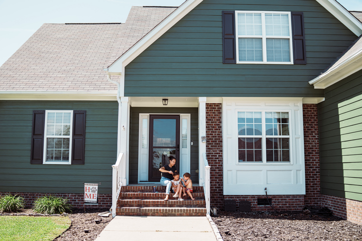 exterior of a house with mother and children playing outside
